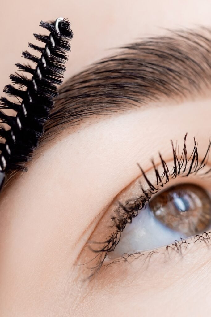 Master with comb of eyebrow hair in women, brow correction in beauty salon